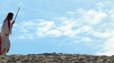 Cüppe ve kuşak personel ile Yorgun İsa zor kumlu tepelerde yürürken