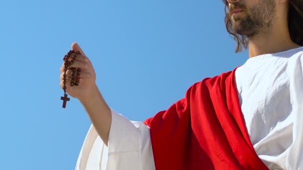 真剣なイエスは、天にロザリオを上げ、神、キリスト教の宗教のシンボルを祈ります — ストック動画