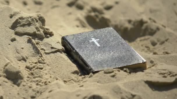 Священная Библия, брошенная в песке, забытые древние знания, старая отвергнутая религия — стоковое видео