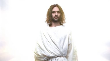 Merciful Jesus looking into camera against shining background, grace of Lord clipart