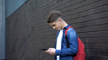 Okul çocuğu arka bahçesinde cep telefonu kullanarak, mobil oyunlar, sosyal medya bağımlılığı