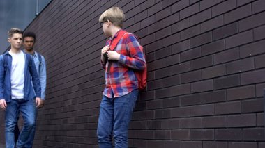 Korkmuş çocuk lise öğrencilerine bakıyor, zorbalık kurbanı sindirilmiş