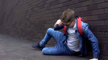 Yumruklu okul çocuğu arka bahçede acı hissederek yatarken, zorbalık kurbanı sindirdi