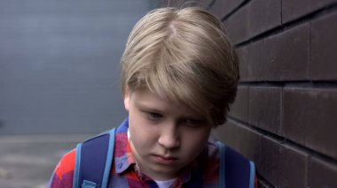 Duvara yakın yalnız duran üzgün genç öğrenci, zorbalık kurbanı, depresyon