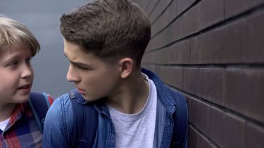 Kıskanç genç çocuk sınıf arkadaşına kötü şeyler söylüyor, sözlü taciz, gözdağı