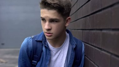 Üzgün genç öğrenci duvara yakın yalnız ayakta, zorbalık kurbanı, depresyon