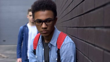 Duvara yaslanmış, arkasında suçlu korkmuş kabadayı afrikalı-Amerikalı çocuk