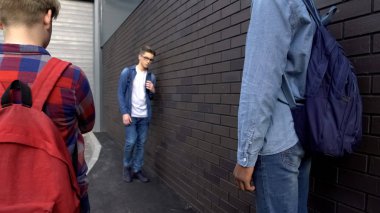 Holiganlar okulun arka bahçesinde zayıf çocuğu tehdit ediyor, zorbalık ediyor, çatışmayı kışkırtıyor