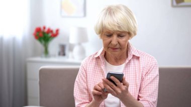 Ciddi yaşlı kadın yeni akıllı telefon kullanarak öğrenme, yaşlılar için teknoloji