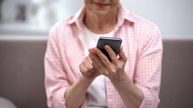 Akıllı telefon kullanan gülümseyen yaşlı kadın, yaşlılar için uygulama, teknoloji