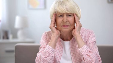Yaşlı kadın masaj tapınaklar, migren ağrısı hissi, sağlık sorunları