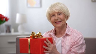 Gülümseyen kıdemli kadın tutan hediye kutusu, mutluluk, kadınlar günü kutlama