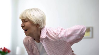 Yaşlı bayan sırtkeskin ağrı hissi tutarak, yaşlılıkta spinal sağlık sorunu