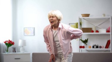 Yaşlı kadın kanepeden ayakta aniden keskin bel ağrısı, spazm hissi