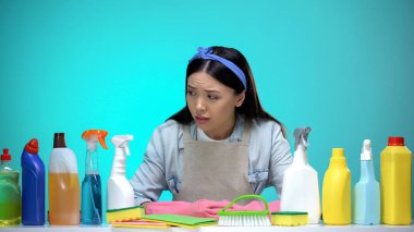Deterjanlar, zor seçim, ev işleri ile masaya bakan çaresiz ev kadını