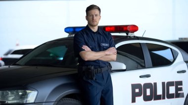 Devriye arabasına yaslanmış elleri çapraz üniformalı profesyonel polis, görev