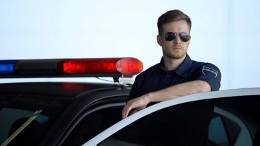 Polis arabasının kapısının yanında duran güneş gözlüğü izleme yol ciddi devriye
