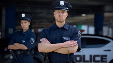 Devriye arabasının yanında üniformalı kendine güvenen erkek ve kadın polis memurları