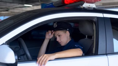 Yorgun polis kadın şapka ayarlama, takım arabada oturan, yorgun alt iş