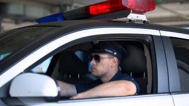 Güneş gözlüğü içinde kendinden emin polis arabada oturan, alan devriye görevi için hazır