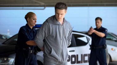 Suçluları tutuklayan polisler, silah doğrultan erkek memur, kelepçe takan polis kadın