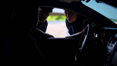 Arabada sürücüile konuşan memurlar, trafik suçu şüphesi, önleme