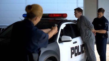 Devriye aracının yakınında tehlikeli holigan ları tutuklayan polis memurları, tabancayı hedef alıyor