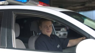 Polis arabasından kameraya bakan gülen polis, önemli meslek