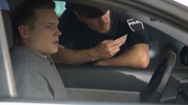 Polis, şüpheli adamın araçtaki belgelerini, sahte sürücü ehliyetini kontrol ediyor