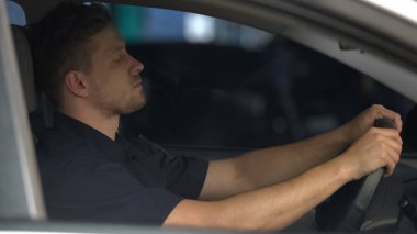 Yorgun polis memuru arabada otururken gözlerini kapattı, stresli günün ardından bitkin