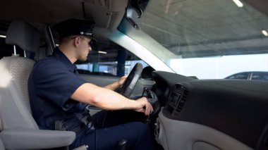 Devriye arabasında oturan kendine güvenen polis, sürücü için ateşleme anahtarlarını çeviriyor