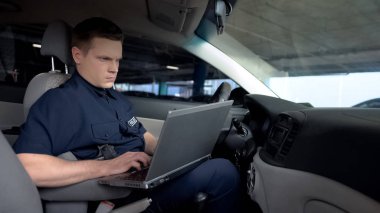 Devriye arabasında dizüstü bilgisayar üzerinde çalışan polis, olay haritasını izleme, teknoloji