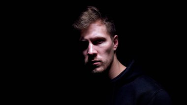 Karanlık arka plana karşı duran korkmuş çürük adam, holigan kurbanı, yakın çekim