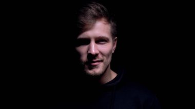 Çılgın sırıtış ile tehlikeli adam karanlık arka plan karşı kamera içine bakıyor