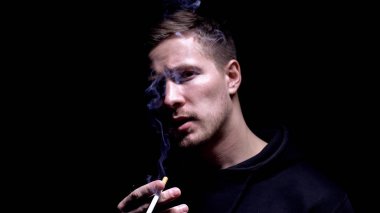 Sigara içen ve kameraya bakan adam, kötü alışkanlık sorunu, bağımlılık