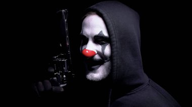 Silahlı çılgın palyaço adam uğursuzca kameraya bakıyor, katil tehdit