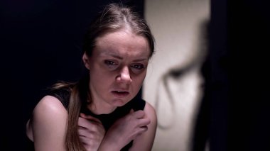 Odada korkmuş şiddet kurbanı, arkasında kemer ile adam gölgesi, cinsel kölelik