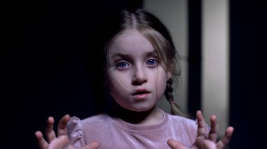Küçük kadın çocuk korkmuş, kameraya bakıyor, karanlıktan korkuyor, hayaletler fobisi var