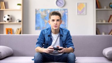 Odaklanmış genç çocuk evde video oyunu oynarken, garip yaşta gadget bağımlılığı
