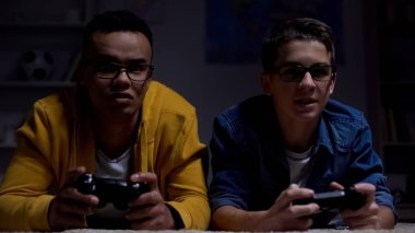 Endişeli Afrikalı-Amerikalı ve kafkas çocuklar video oyunu oynarken, procrastinators
