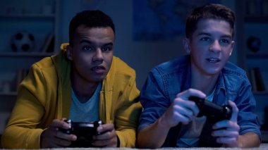 Çok ırklı arkadaşlar gece geç saatlerde video oyunları oynarken, tembel üniversite öğrencileri