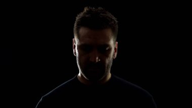 Gölgede üzgün erkek utanarak aşağı bakıyor, sorun hayal kırıklığı, pişmanlık