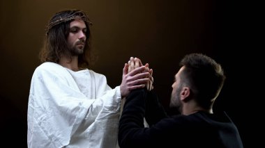 İsa Mesih dua eden adamın el ele tutuşarak, dini destek, günahları bağışlama