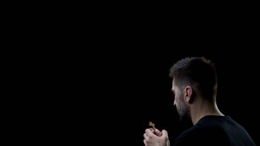 Siyah arka planda tahta haç tutan duaeden adam, Tanrı'ya inanç