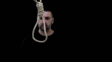 Umutsuz erkek siyah arka plan üzerinde ip döngü bakıyor, intihar