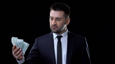 Takım elbiseli başarılı ciddi adam elinde dolar bakarak, yatırım projesi