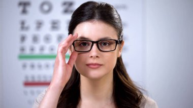 Optik mağazada kamera bakarak yeni gözlük genç kadın, satın