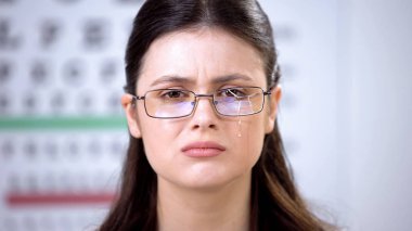 Kırık gözlüklü üzgün bayan kameraya bakıyor ve kötü görme acı ağlıyor