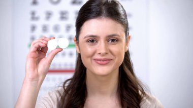 Kamerada kontakt lens ile durumda gösteren gülümseyen bayan, görme ekipmanı seçimi