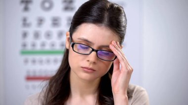 Gözlükte baş tutan, migren ağrısı hisseden, belirti de bulunan mutsuz kadın